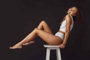 Side view cropped portrait of young beautiful woman sitting on white chair