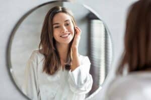 Woman smiling while looking in the mirror please with her Renuva Fat Transfer results